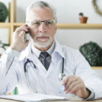 Doktor vid skrivbord som talar i telefon